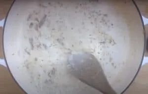 Creamy sauce with herbs being stirred in a pan, perfect for pasta or chicken dishes. Cooking close-up.